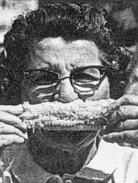 black and white of a women with glasses easting corn on the cob