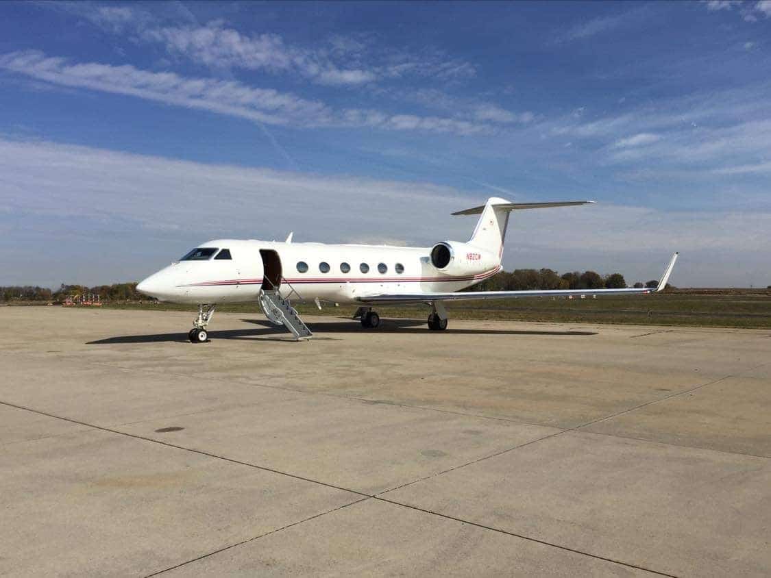 Private jet parked on tarmac under clear sky