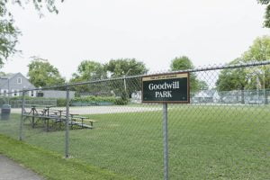 Goodwill Park sign on fence, picnic area, greenery.