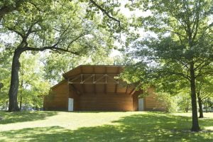Wooden building surrounded by green trees in a park.