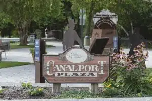 Canalport Plaza sign with flowers in park setting.