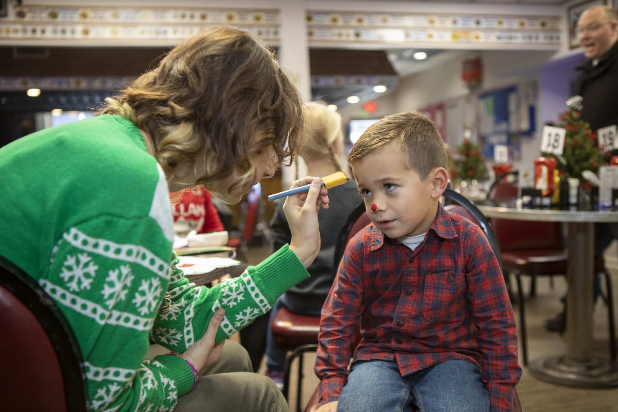 Child getting face painted at holiday event.