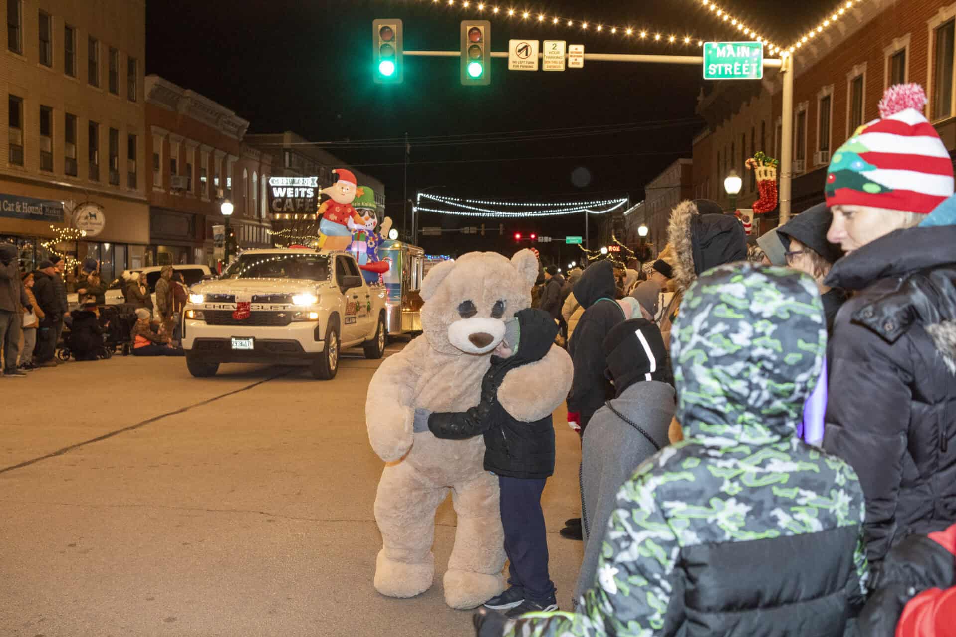Holiday parade crowd beneath glowing downtown street lights