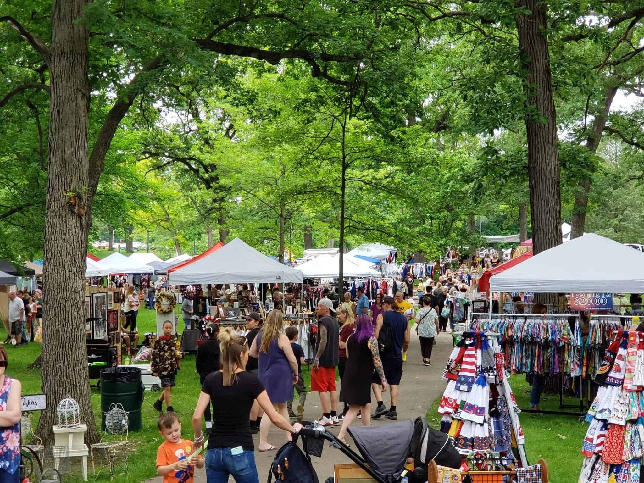 Crowded outdoor market beneath leafy trees