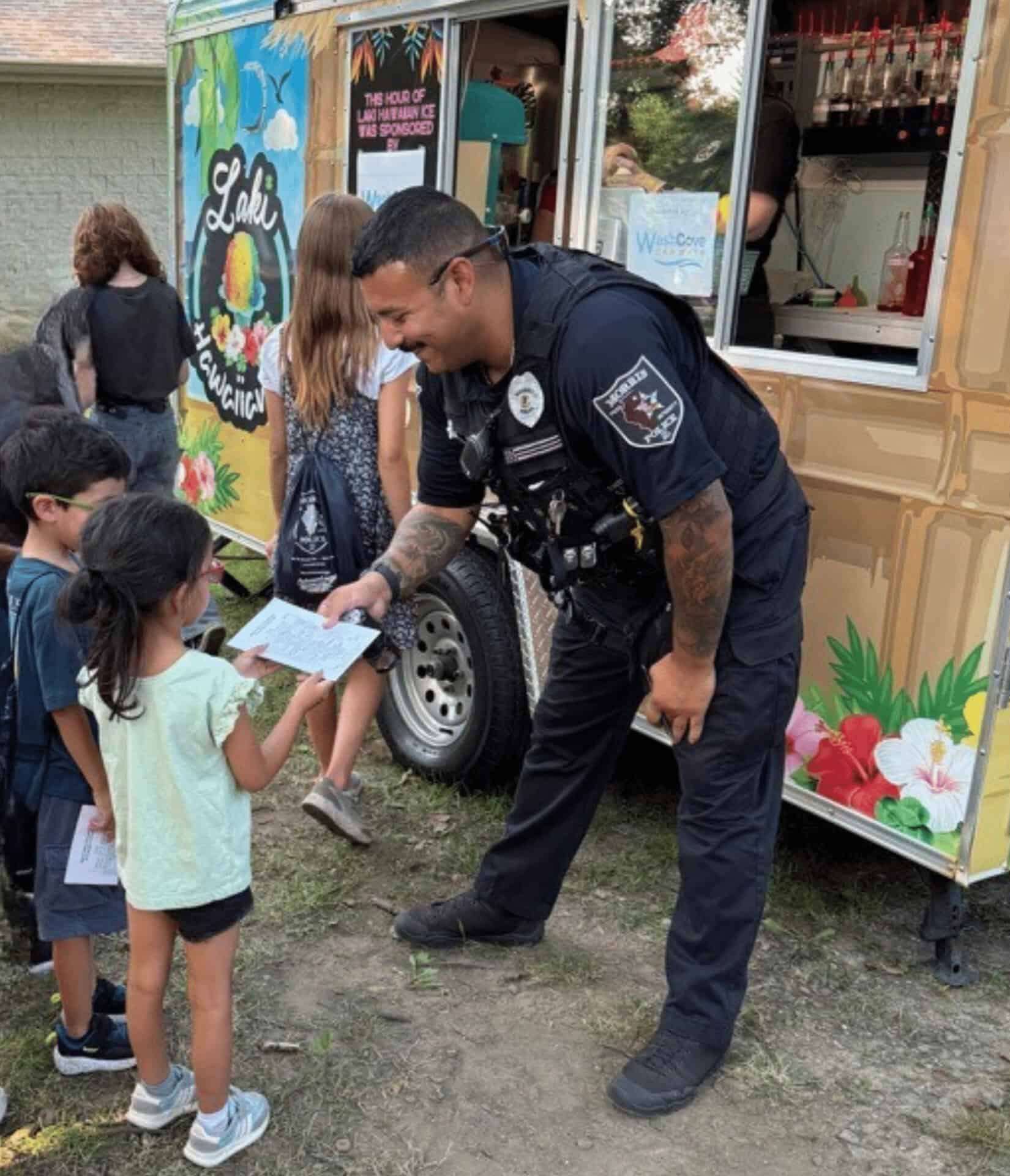 Police officer greeting children beside colorful food truck